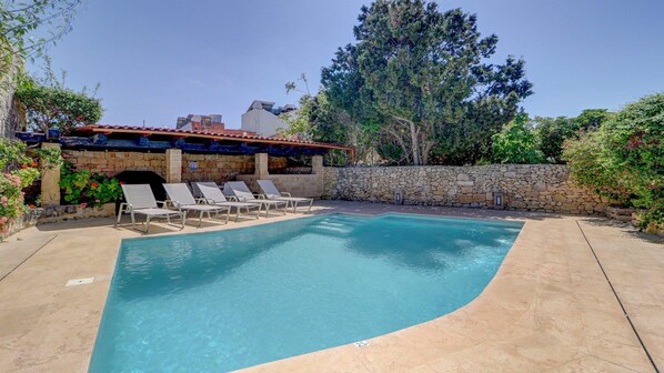 A swimming pool with lounge chairs, a stone wall, and a stone building with a red roof. - Wonderful 4BR Farmhouse with Private Pool (Rabat)
