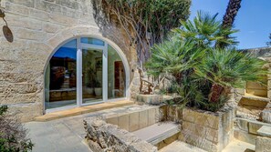 A stone building with a glass entrance, outdoor seating, and a palm tree. - Wonderful 4BR Farmhouse with Private Pool (Rabat)