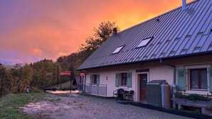 A building with a sloped roof, a covered outdoor seating area, and a gravel driveway. - Auberge du Graber (Dolleren)