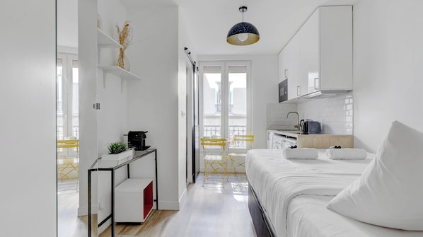 Ein modernes Hotelzimmer mit Bett, Schreibtisch, einer Kaffeemaschine und Blick auf die Stadt.