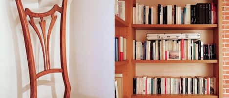 A wooden chair with a woven seat and a bookshelf with multiple shelves filled with books.