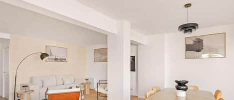 Ein modernes Wohnzimmer mit einer Couch, einem Couchtisch und einem Essbereich mit Tisch und Stühlen.