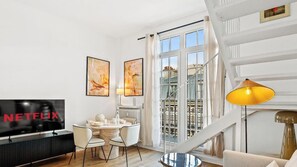 Ein modernes Wohnzimmer mit Flachbildfernseher, Essbereich und Treppe.
