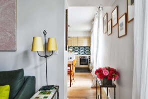 Ein modernes Wohnzimmer mit einer Couch, einer Stehlampe und einem Tisch mit Blumen in einer Vase.
