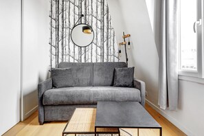 Ein modernes Wohnzimmer mit einem grauen Sofa, einem runden Spiegel und einem schwarzen Couchtisch.
