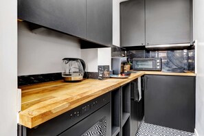 Eine moderne Küche mit einer Holzausziehtheke, einer Kaffeemaschine, einer Mikrowelle und einem eingebauten Backofen.