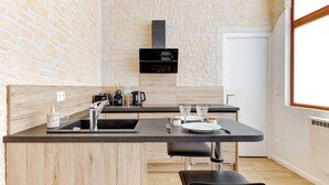 Een moderne keuken met een stenen muur, een zwarte afzuigkap en een eethoek met een tafel en stoelen.