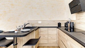Een moderne keuken met een bakstenen muur, houten kastjes en een zwart aanrecht.