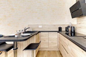 Eine moderne Küche mit Backsteinwand, Holzschränken und einer schwarzen Arbeitsplatte.