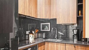 A modern kitchen with dark countertops, wooden cabinets, a stainless steel sink, and a coffee maker. - Elegance parisienne proche Opera et Montmartre (Paris)