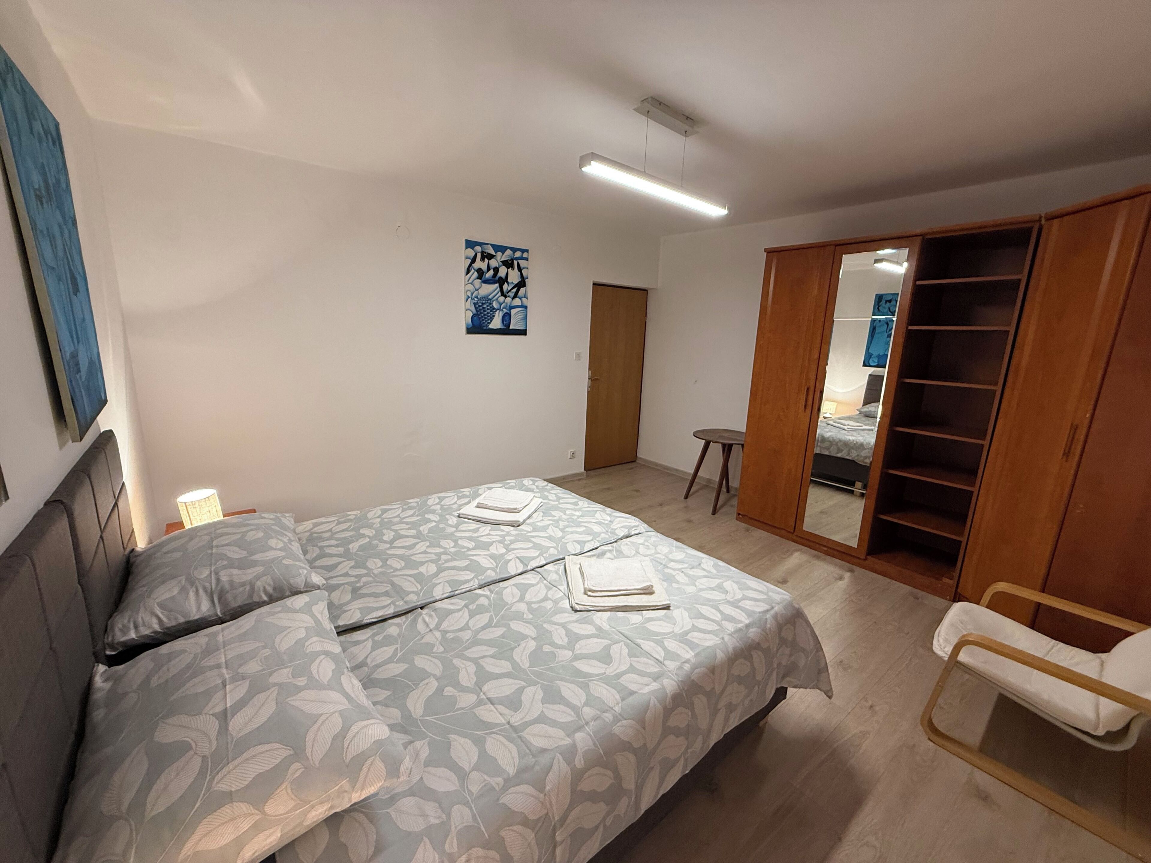 A bedroom with a bed, a wardrobe, a chair, and a small table.