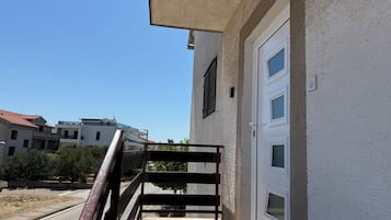 Ein Gebäude mit weißer Fassade, einer Glastür und einem Metallgeländer, das zu einem Balkon führt.