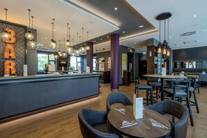 A modern bar area with a counter, seating, and pendant lighting. - Premier Inn Halle (Saale) City Centre (Halle (Saale))