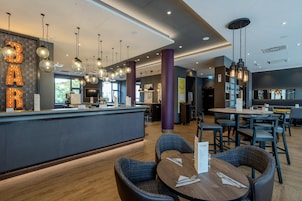 Un espacio de bar moderno con mostrador, asientos e iluminación colgante.
