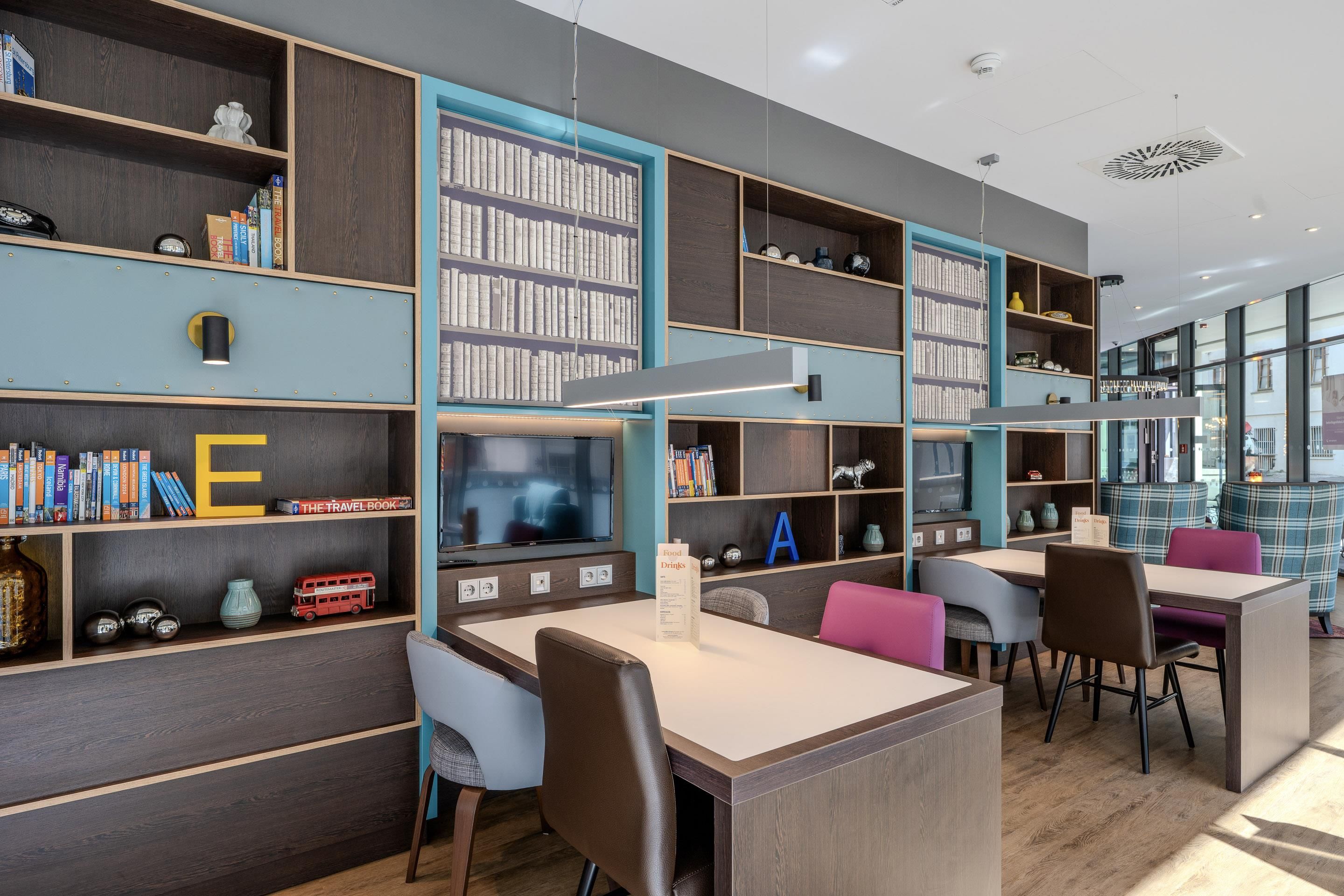 Une bibliothèque moderne dotée d’étagères, d’espaces de lecture et d’un téléviseur.