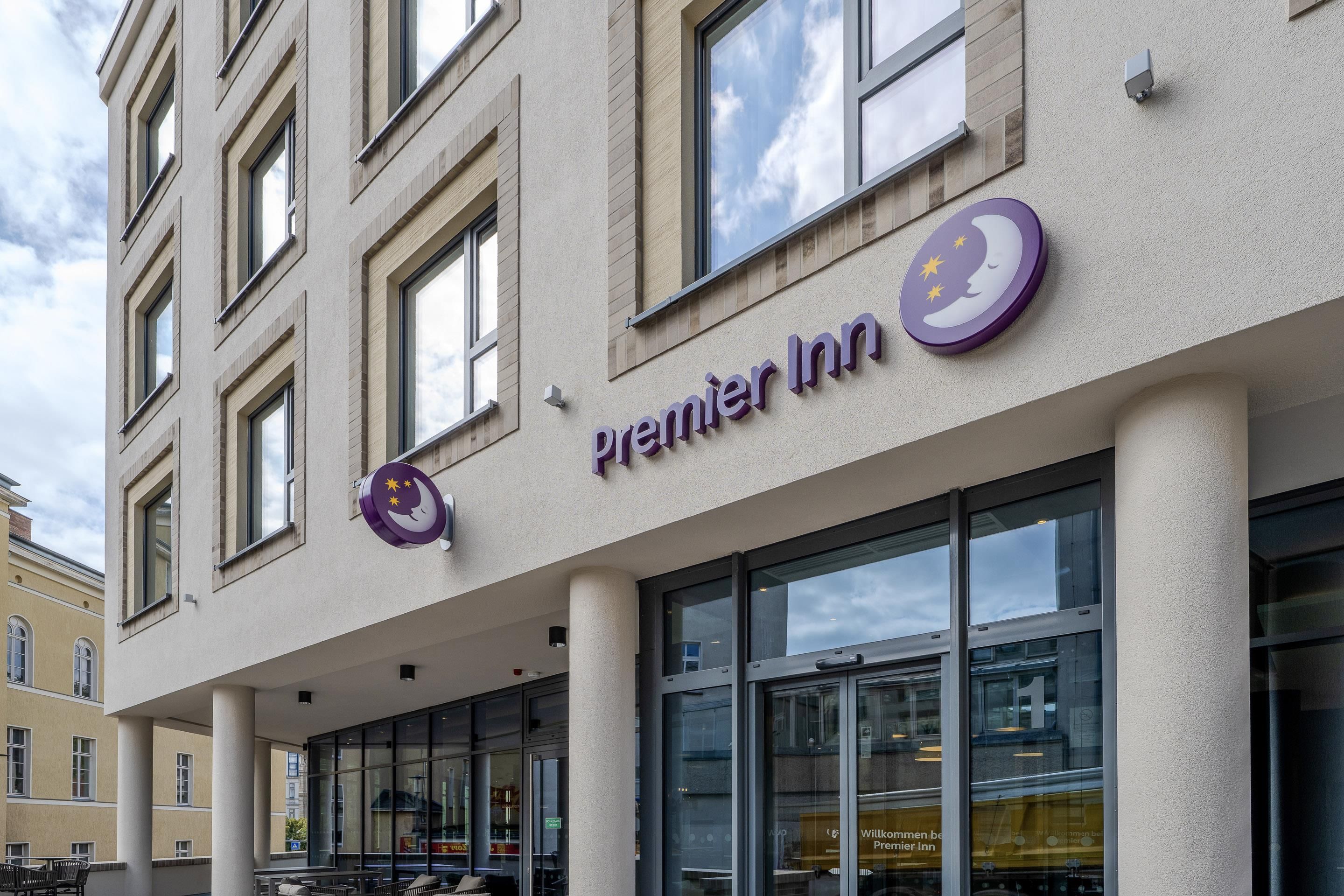 La façade d'un hôtel, avec une enseigne « Premier Inn » bien visible, de grandes fenêtres et un style architectural moderne.
