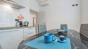 Une cuisine moderne avec des meubles blancs, un plan de travail et une machine à café.
