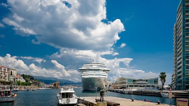 Un navire de croisière était amarré dans un port, avec des bâtiments et une statue visibles au premier plan.