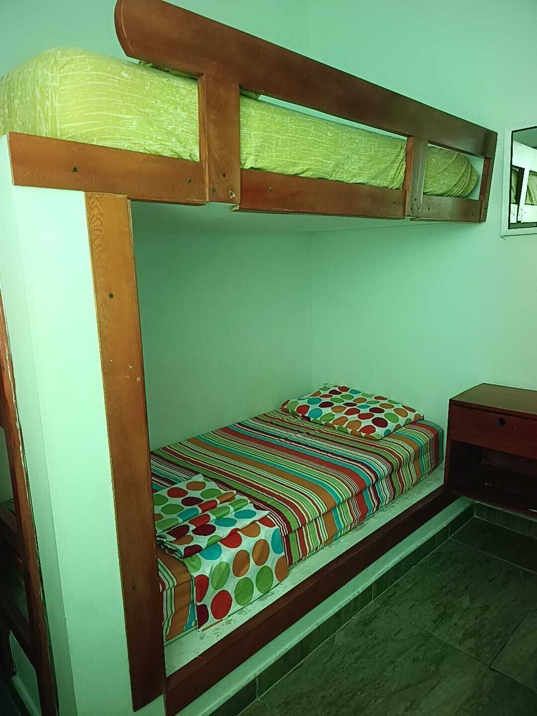 A bunk bed with a wooden frame and a colorful bedspread.