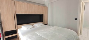 A bedroom with a bed, wooden wardrobe, and a door. - Central Ostend Apt: Family-Friendly Comfort (Oostende)