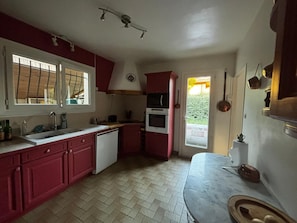 A kitchen with a sink, stove, and cabinets, a window, and a door leading outside. - 3-Bedroom House for 6 People in Mimizan (Mimizan)