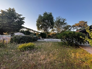 A garden with various plants, a pathway, and a building with a red roof. - 3-Bedroom House for 6 People in Mimizan (Mimizan)