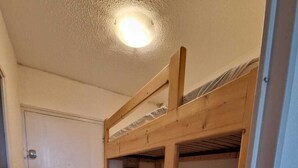 Ein Zimmer mit einem Etagenbett, einer Tür und einer Deckenleuchte.