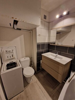 Ein kleines Badezimmer mit Toilette, Waschbecken und einer kleinen Ablage.