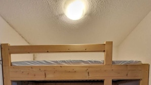 Ein Etagenbett mit einer Leiter, einer Matratze und einem Wandheizgerät.