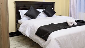 A hotel room with a bed, a wooden headboard, and a marble-patterned floor. - Lovely 2-bedroom apartment in beautiful Thika for a relaxing stay (Thika)