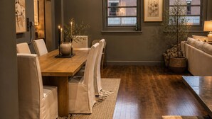 Un comedor moderno con una mesa de madera, sillas blancas acolchadas y una alfombra estampada.