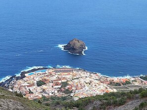 A coastal town with buildings, a rocky outcrop, and a beach.
