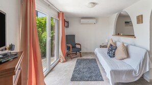 Een kamer met een bank, een stoel, een televisie en een raam met gordijnen.
