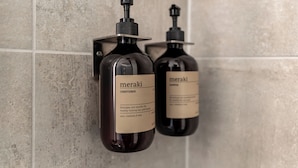 Zwei Flaschen Meraki Conditioner auf einer gefliesten Wand.