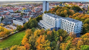 Ein modernes, mehrgeschossiges Gebäude, umgeben von Herbstlaub.