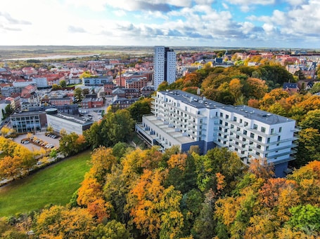 A modern building with multiple floors, surrounded by autumn foliage.. Hotel Kongens Ege
