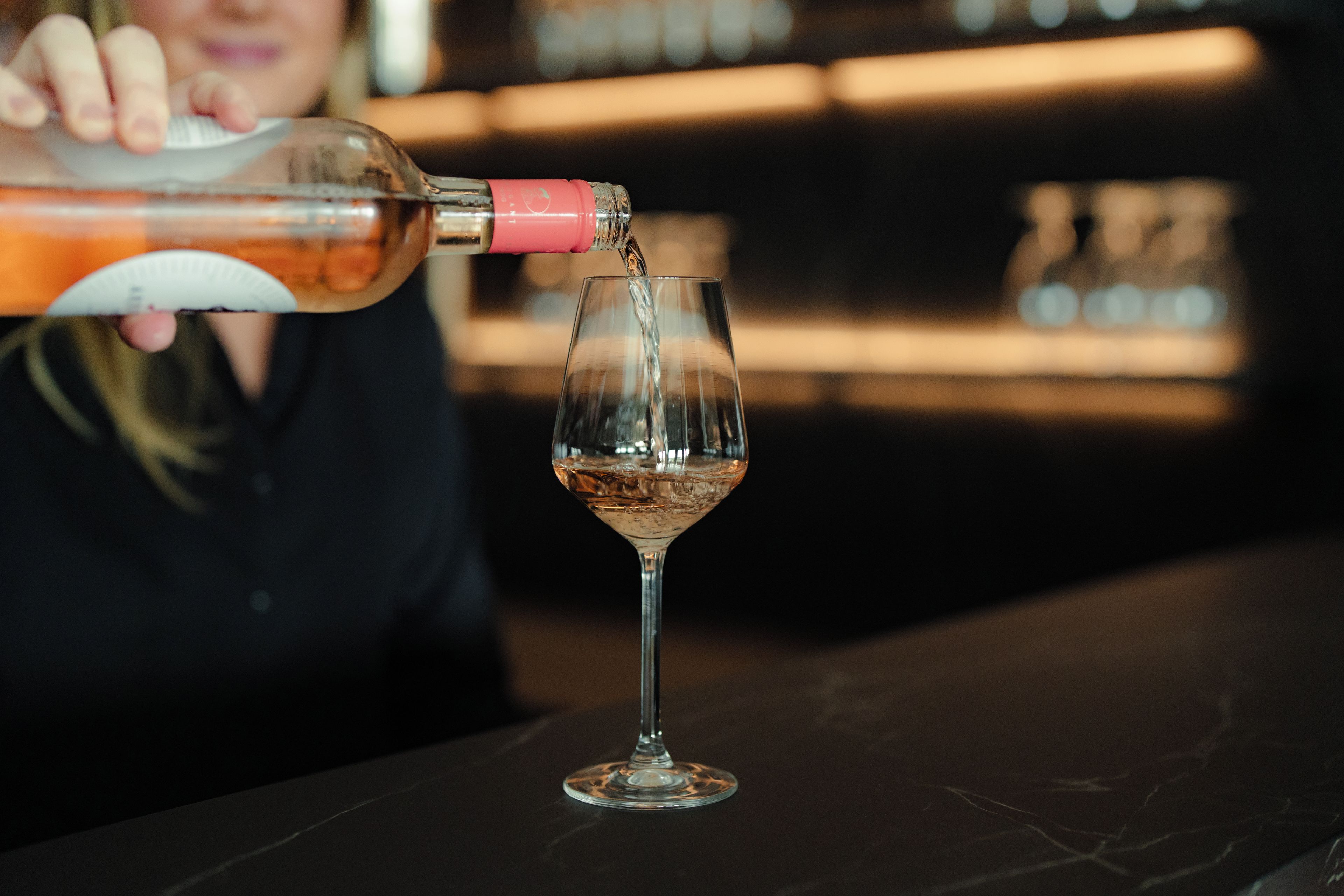 Eine Person gießt Flüssigkeit aus einer Flasche in ein Glas.