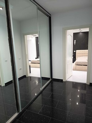 A modern hotel room with a large mirror, a bed with a beige headboard, and a black tiled floor. - Florence Luxury Apartment Mamaia Beach Constanta Romania (Mamaia-Sat)