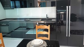 Eine moderne Küche mit einer Glasinsel, Edelstahlgeräten und einem Essbereich mit einem Holzbstuhl.