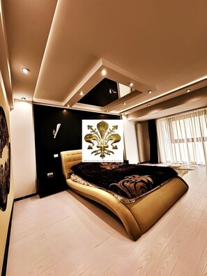 A modern bedroom with a curved bed, recessed lighting, and a large window with curtains. - Florence Luxury Apartment Mamaia Beach Constanta Romania (Mamaia-Sat)