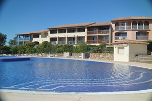Ett hotell med en swimmingpool, flera balkonger och en klar himmel.