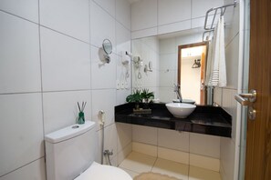 Ein Badezimmer mit Toilette, Waschbecken, Spiegel, Handtuchhalter und Dusche.