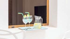 Una mesa blanca con dos vasos de una bebida transparente, una jarrón y una ventana que muestra una escalera.