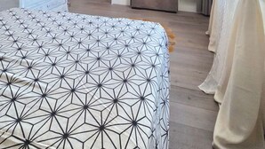 Een slaapkamer met een bed, een dressoir, een tv op een standaard, een kledingkast en een raam met gordijnen.