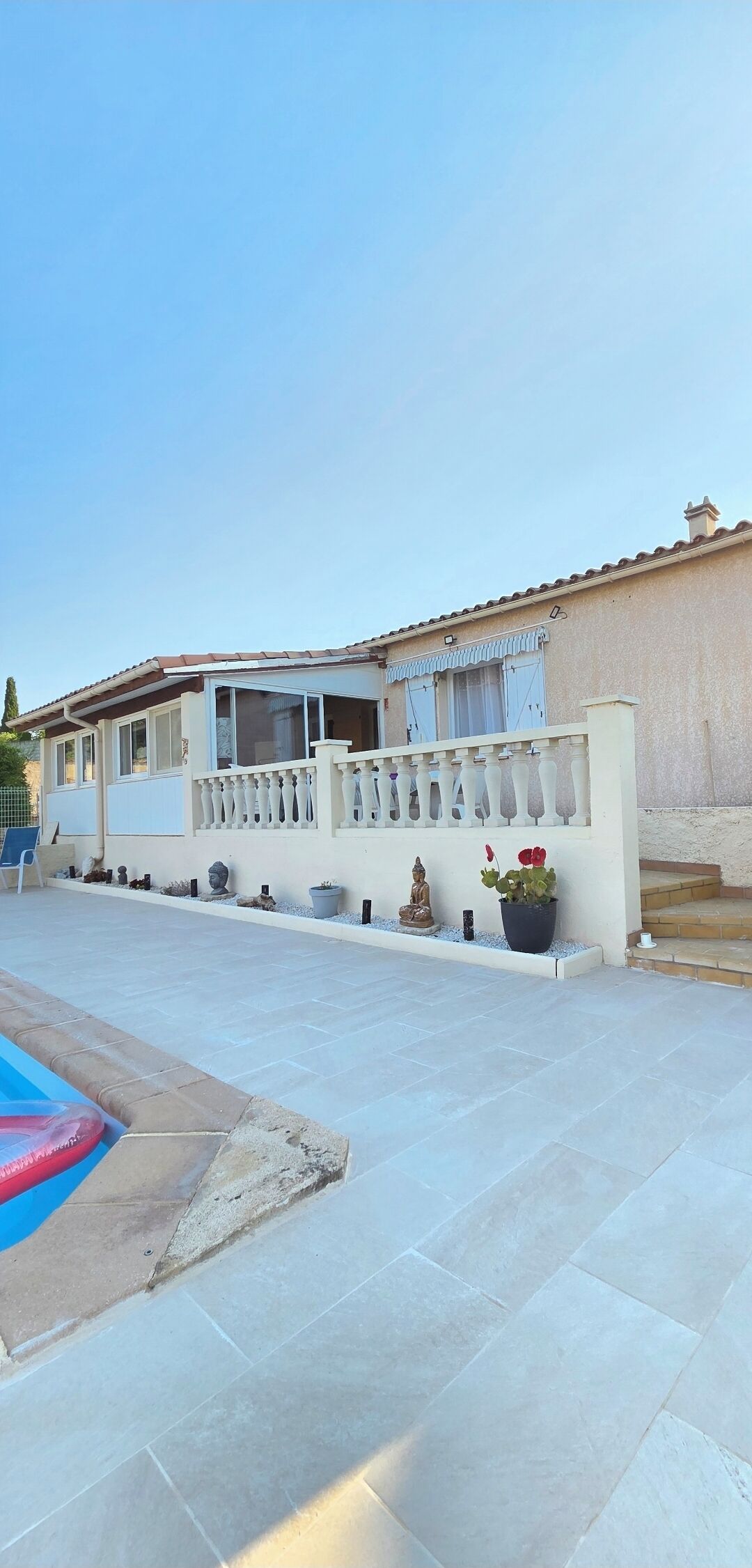 A building with a tiled patio, a swimming pool, and a statue.