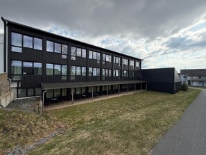 A modern building with a covered outdoor seating area and large windows.