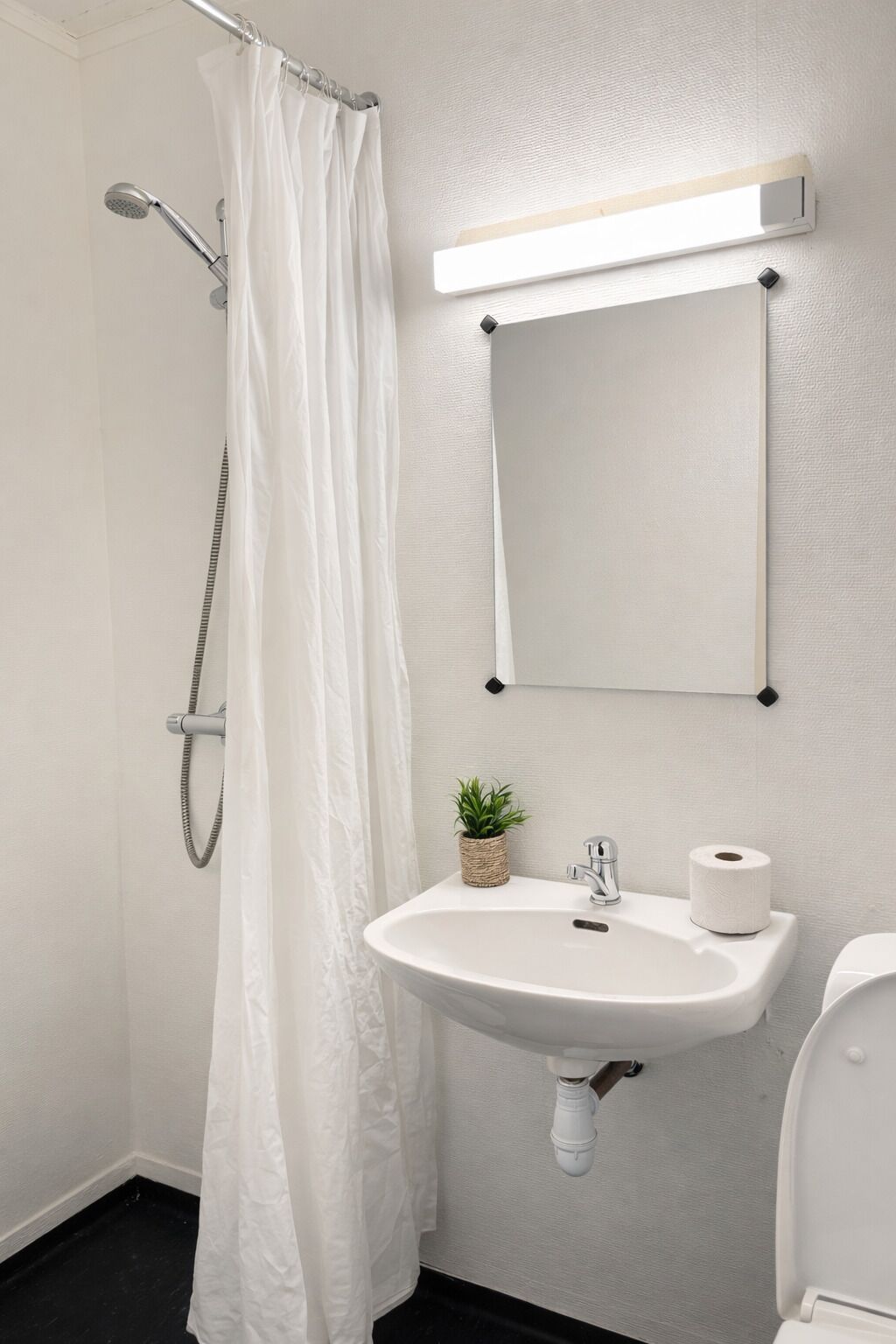 Un baño con ducha, lavabo, inodoro y espejo.