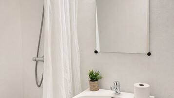Un baño con ducha, lavabo, inodoro y espejo.