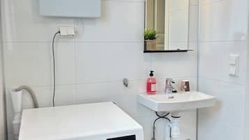A modern laundry room with a Bosch washing machine, a sink, and a mirror.