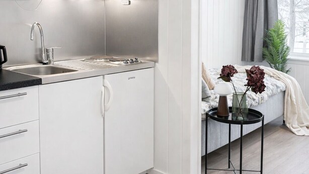 A modern kitchen with white cabinets, stainless steel appliances, and a black countertop. - Rygge Apartments (Moss)